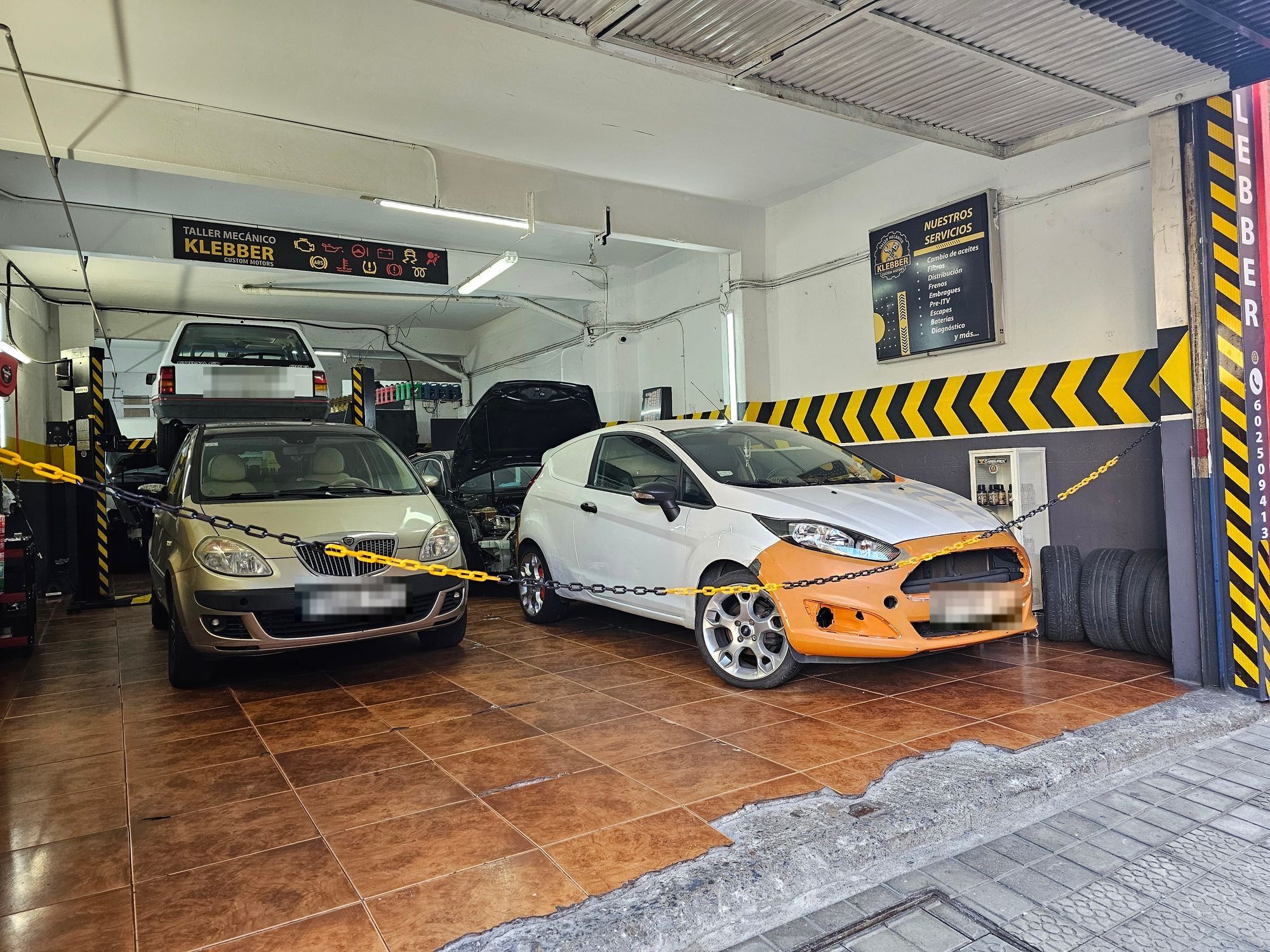 Interior del taller Klebber Custom Motors con coches en reparación
